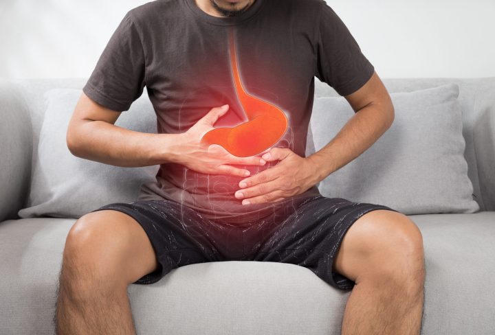 Acid reflux or Heartburn, The photo of stomach is on the men's body against gray Background, Bad health, Male anatomy concept